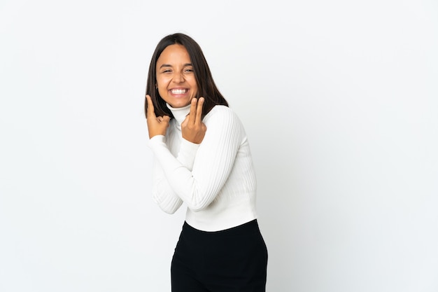 Jonge Latijns-vrouw die op witte achtergrond wordt geïsoleerd die en overwinningsteken glimlacht toont