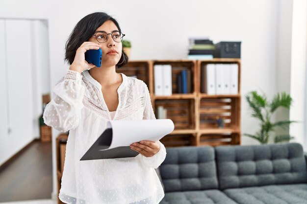 Jonge latijns-vrouw die psychologiesessie heeft en praat op de smartphone in het psychologiecentrum