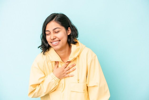 Jonge Latijns-vrouw geïsoleerd op blauwe achtergrond lachen houden handen op het hart, concept van geluk.