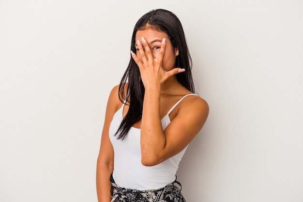 Jonge Latijns-vrouw geïsoleerd op een witte achtergrond knipperen naar de camera door vingers, beschaamd die betrekking hebben op gezicht.