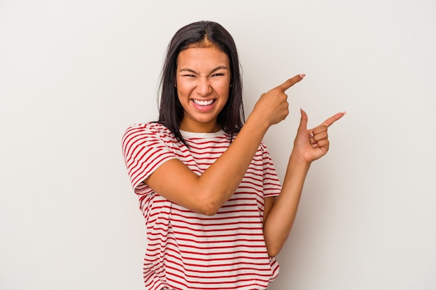 Jonge latijns-vrouw geïsoleerd op een witte achtergrond opgewonden wijzend met wijsvingers weg.