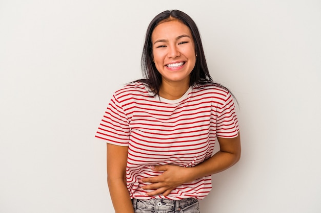 Jonge Latijns-vrouw geïsoleerd op een witte achtergrond raakt buik, glimlacht zachtjes, eten en tevredenheid concept.