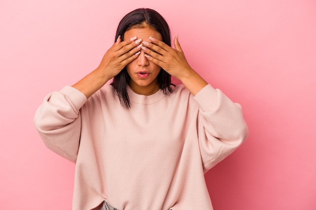 Jonge latijns-vrouw geïsoleerd op roze achtergrond bang voor ogen met handen.