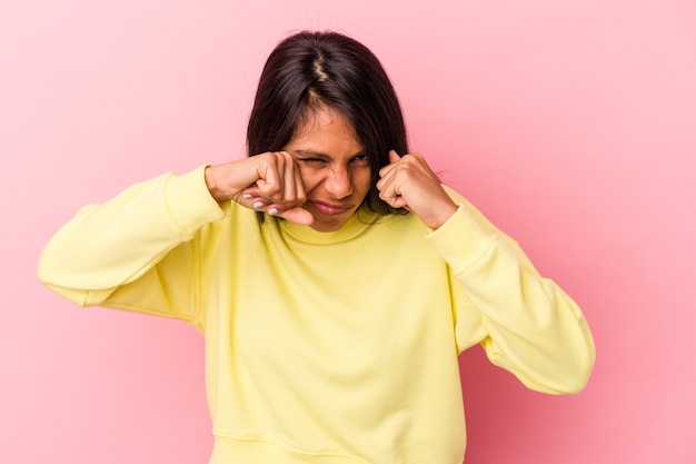 Jonge latijns-vrouw geïsoleerd op roze achtergrond die een vuistslag gooit, woede, vecht vanwege een ruzie, boksen.