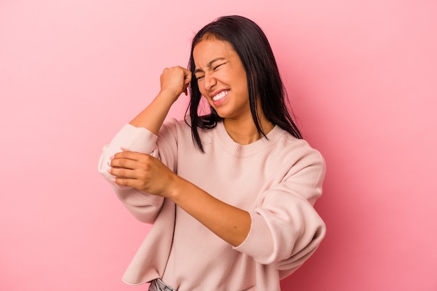 Jonge Latijns-vrouw geïsoleerd op roze achtergrond masseren elleboog, lijden na een slechte beweging.