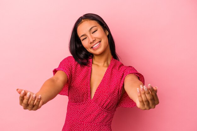 Jonge Latijns-vrouw geïsoleerd op roze achtergrond met een welkome uitdrukking.