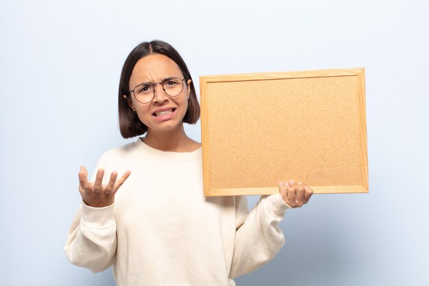 Jonge Latijns-vrouw kijkt boos, geïrriteerd en gefrustreerd schreeuwend wtf of wat er mis is met jou