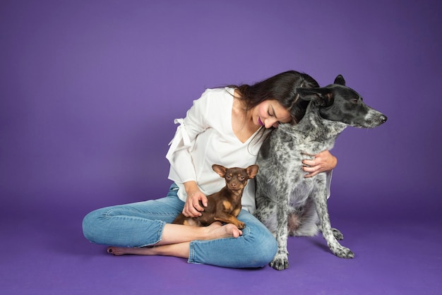 Jonge Latijns-vrouw knuffelt haar chihuahua-hond op een paarse geïsoleerde achtergrond
