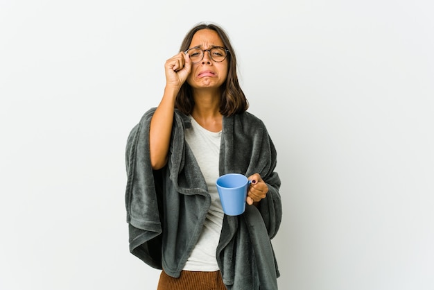 Jonge Latijns-vrouw met deken geïsoleerd op een witte muur troosteloos janken en huilen.