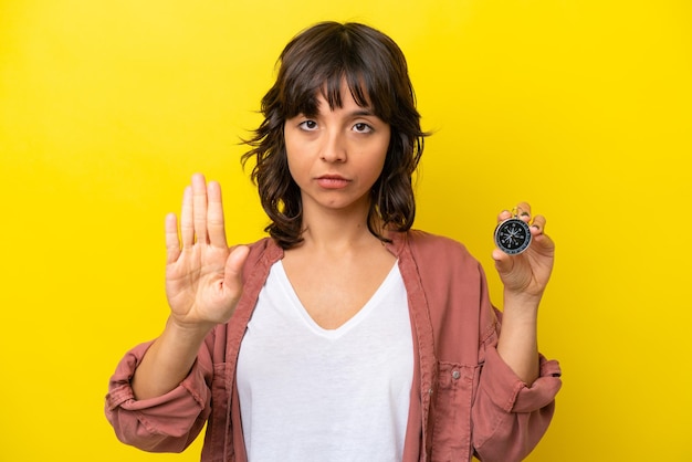 Foto jonge latijns-vrouw met kompas geïsoleerd op gele achtergrond stop gebaar maken