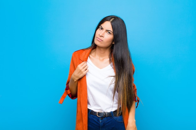 Jonge Latijns-vrouw op zoek arrogant, succesvol, positief en trots, wijzend naar zichzelf op vlakke muur