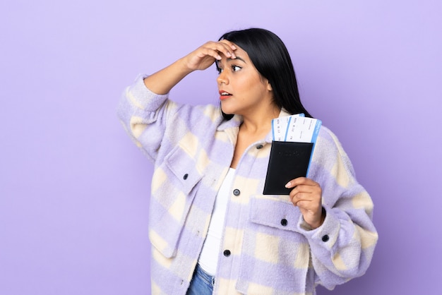 Jonge Latijns-vrouw vrouw op paarse muur in vakantie met paspoort en vliegtickets terwijl op zoek iets in de verte