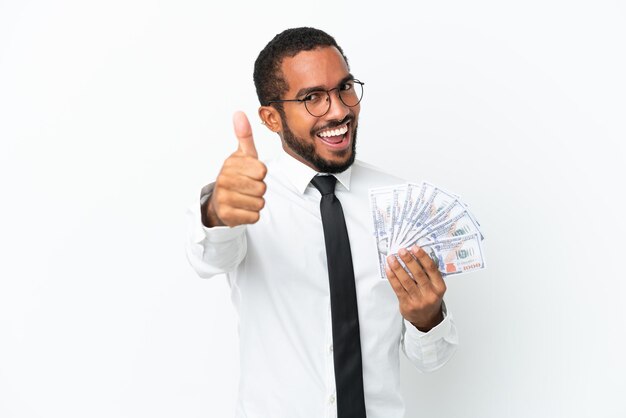 Jonge Latijns-zakelijke man die veel geld neemt geïsoleerd op een witte achtergrond met duimen omhoog omdat er iets goeds is gebeurd