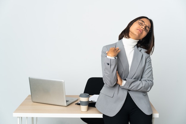 Jonge Latijnse bedrijfsvrouw die in een bureau werkt dat op wit met vermoeide en zieke uitdrukking wordt geïsoleerd