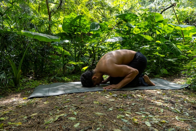 Jonge latijnse man regelt zijn yogamat in een bos op een duidelijk direct contact met de natuur mexico