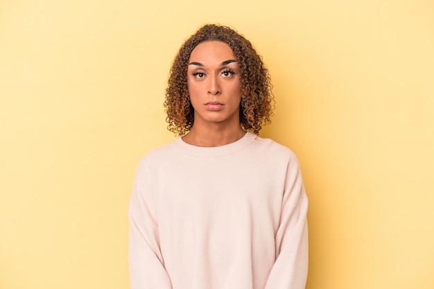 Jonge latijnse transseksuele vrouw geïsoleerd op gele achtergrond verdrietig, serieus gezicht, ellendig en ontevreden.