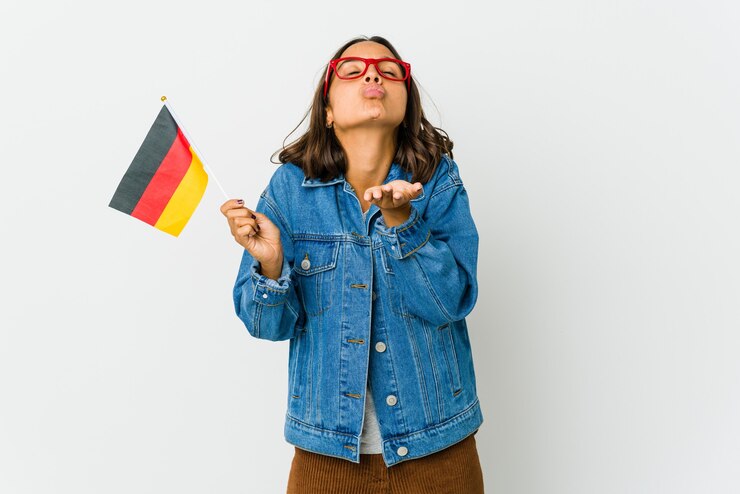 Foto jonge latijnse vrouw die een duitse vlag houdt die op witte muur wordt geïsoleerd die lippen vouwt en palmen houdt om luchtkus te verzenden.
