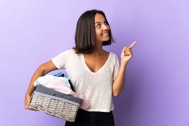 Jonge Latijnse vrouw die een wasmand houdt die op purple wordt geïsoleerd die een groot idee benadrukt