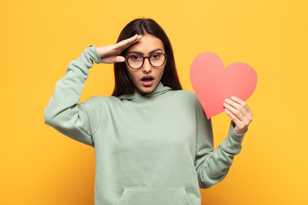 Jonge Latijnse vrouw die er blij, verbaasd en verrast uitziet, lacht en zich verbluffend en ongelooflijk goed nieuws realiseert