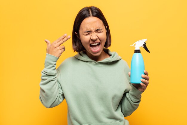 Jonge latijnse vrouw die er ongelukkig en gestrest uitziet, zelfmoordgebaar maakt een pistoolteken met de hand, wijzend naar het hoofd