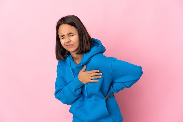 Jonge Latijnse vrouw die op roze achtergrond wordt geïsoleerd die pijn in het hart heeft