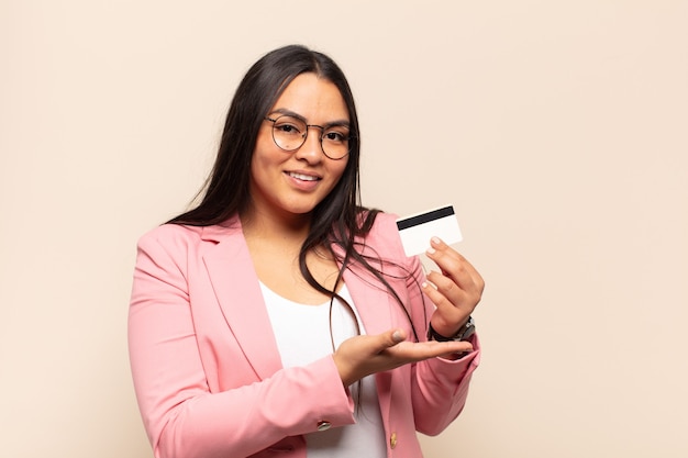 Jonge Latijnse vrouw die vrolijk glimlacht, zich gelukkig voelt en een concept in exemplaarruimte met handpalm toont