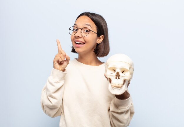 Jonge Latijnse vrouw die zich als een gelukkig en opgewonden genie voelt na het realiseren van een idee, vrolijk vinger opstekend, eureka!