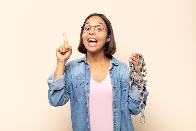 Jonge Latijnse vrouw die zich als een gelukkig en opgewonden genie voelt na het realiseren van een idee, vrolijk vinger opstekend, eureka!