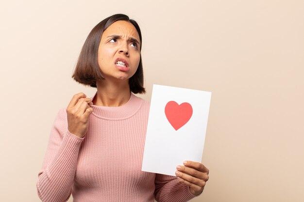 Jonge Latijnse vrouw die zich gestrest, angstig, moe en gefrustreerd voelt, aan de hals van het shirt trekt, gefrustreerd kijkt door het probleem