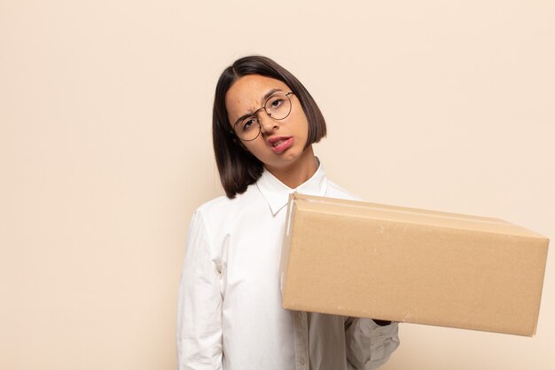 Jonge Latijnse vrouw die zich verbaasd en verward voelt, met een domme, verbijsterde uitdrukking op zoek naar iets onverwachts