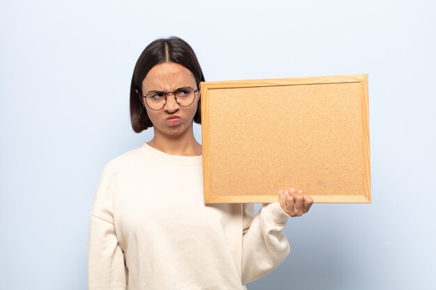 Jonge Latijnse vrouw die zich verdrietig, overstuur of boos voelt en naar de zijkant kijkt met een negatieve houding, fronst van onenigheid