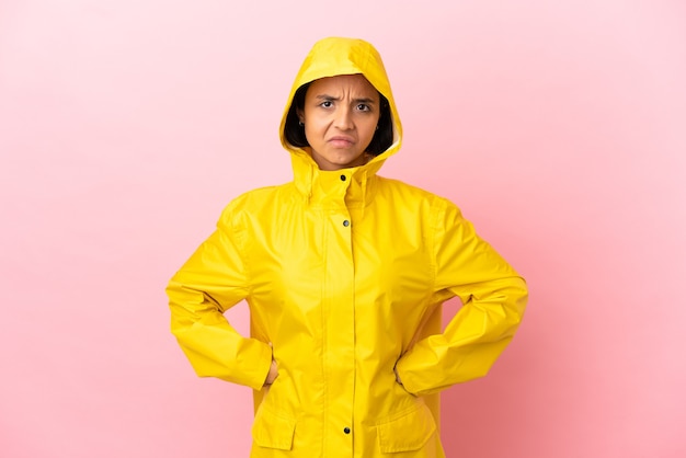 Jonge latijnse vrouw draagt een regenbestendige jas over geïsoleerde achtergrond boos background