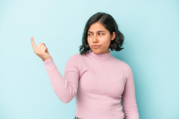 Jonge latijnse vrouw geïsoleerd op een blauwe achtergrond die met de vinger naar je wijst alsof uitnodigend dichterbij komt.