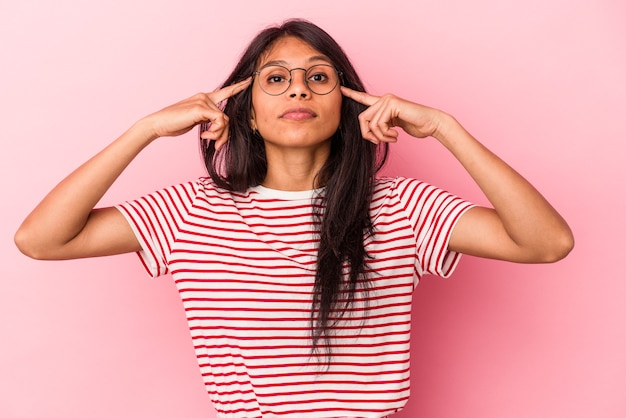 Jonge latijnse vrouw geïsoleerd op roze achtergrond gericht op een taak, wijsvingers wijzend hoofd houden.