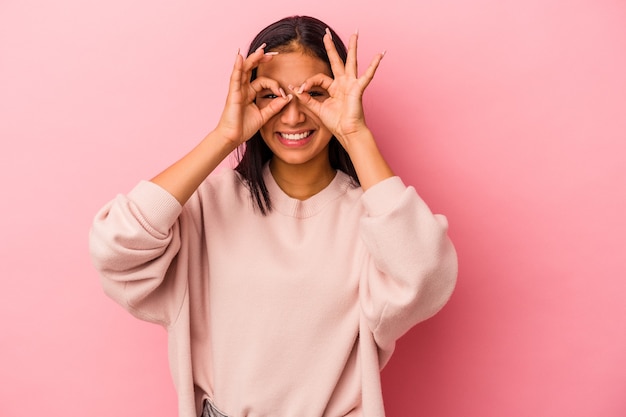 Jonge latijnse vrouw geïsoleerd op roze achtergrond met goed teken boven de ogen