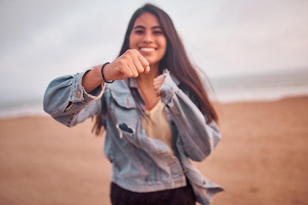 Jonge Latijnse vrouw glimlacht tijdens een prachtige zonsondergang Gelukkige jonge vrouw met masker op het strand