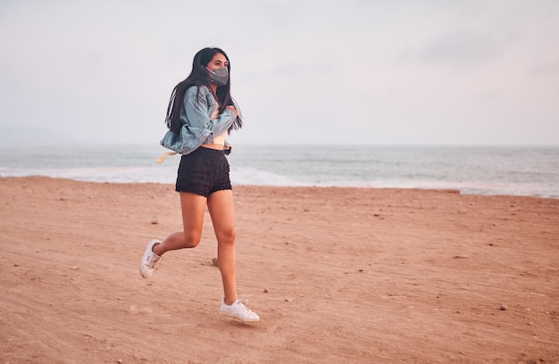 Jonge Latijnse vrouw glimlacht tijdens een prachtige zonsondergang Gelukkige jonge vrouw met masker op het strand