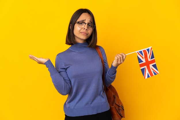 Jonge latijnse vrouw met een vlag van het Verenigd Koninkrijk geïsoleerd op een geel oppervlak met twijfels