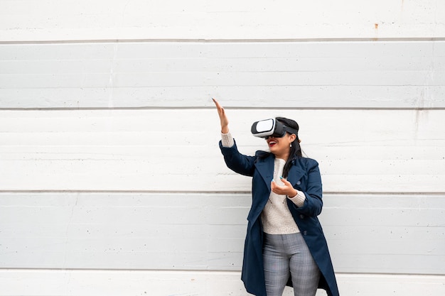 Jonge latijnse vrouw met vrijetijdskleding met een virtual reality-bril gebaren