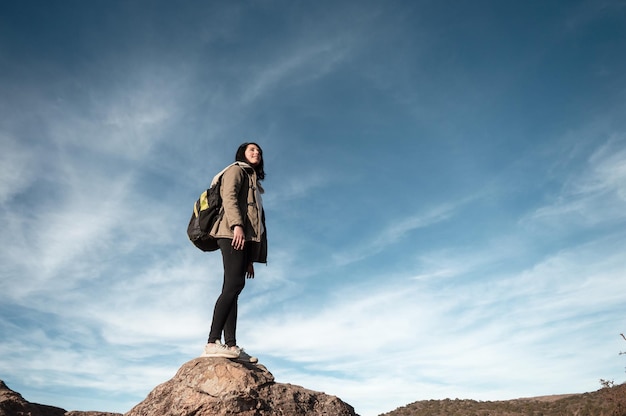 jonge Latijnse vrouw toerist die op een steen staat en over het landschap nadenkt