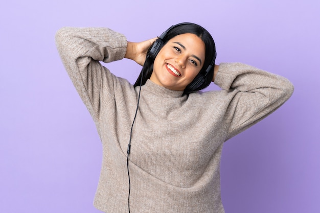 Jonge Latijnse vrouwenvrouw die op purpere het luisteren muziek wordt geïsoleerd