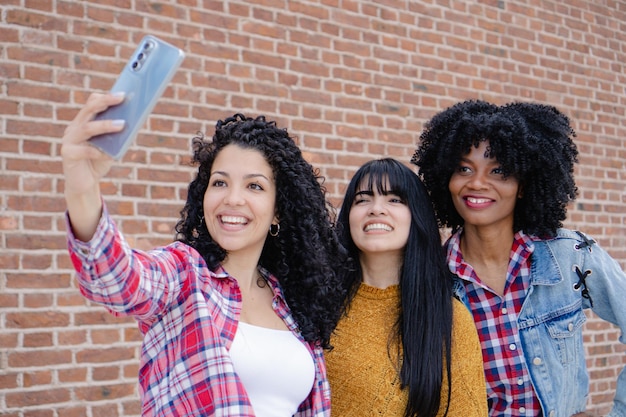 Jonge Latina en Spaanse vrouwen die een selfie maken in de stad met een bakstenen achtergrond