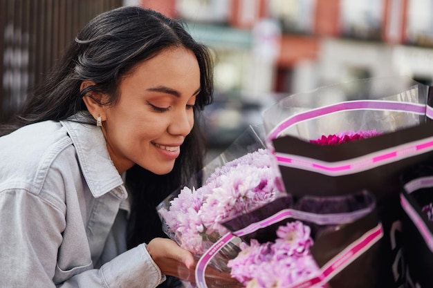 Jonge Latina-vrouw geniet van de geurige schoonheid van kleurrijke bloemen bij het kraampje van een straatverkoper