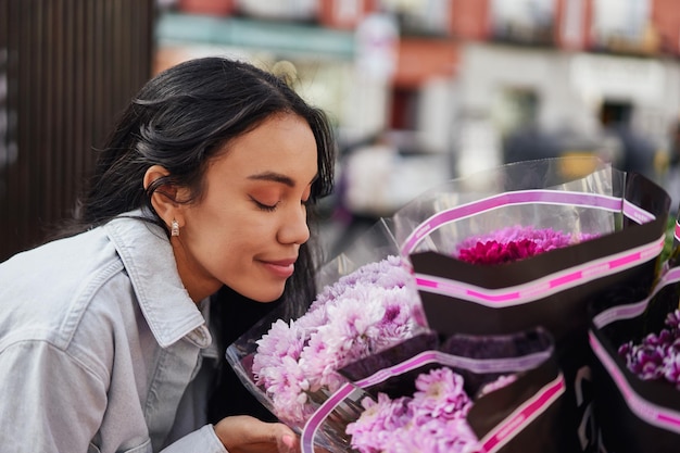 Jonge Latina-vrouw geniet van de geurige schoonheid van kleurrijke bloemen bij het kraampje van een straatverkoper