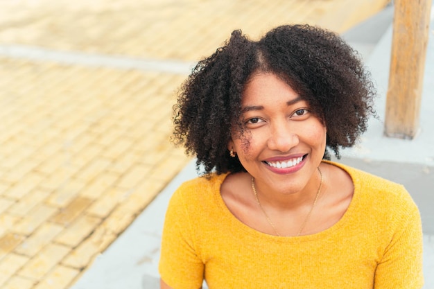 Jonge latina-vrouw met afro die naar de camera kijkt