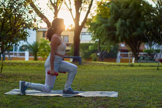 Jonge latina vrouw oefeningen met halters in parkxa