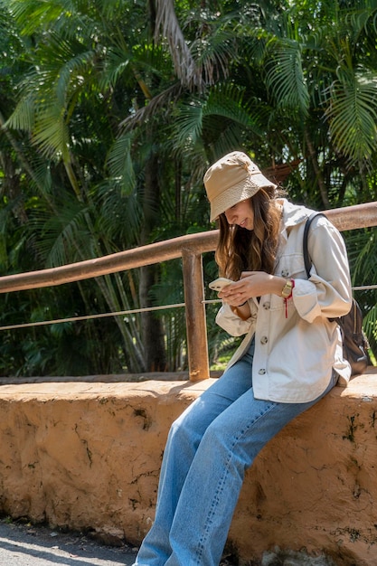 Jonge latina-vrouw op haar mobiele telefoon of smartphone die op safari in het buitenland reist, zon en mobiele telefoon mexico