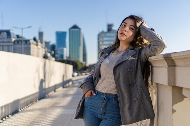 Jonge latina zakenvrouw leunend op een stadsreling kijkend naar de camera