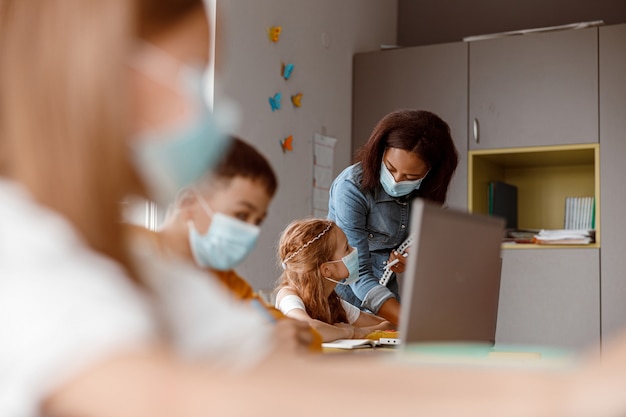 Jonge leraar die schoolmeisje helpt tijdens een les op school