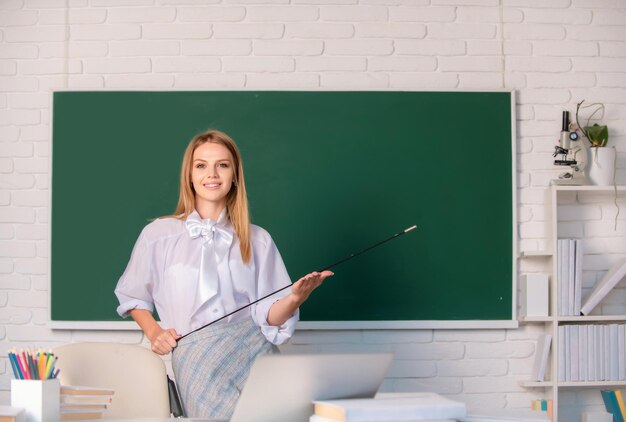 Jonge leraar met aanwijzer Mooie student schattige blonde jonge vrouw in de klas op school